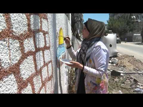 Palestinian artist paints on damaged building in Gaza