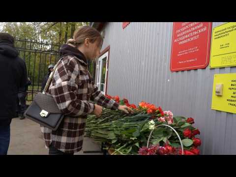 Police stand guard as mourners leave flowers after deadly Russian shooting
