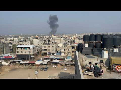 Gazans cook bread on rooftop, as smoke billows from strike