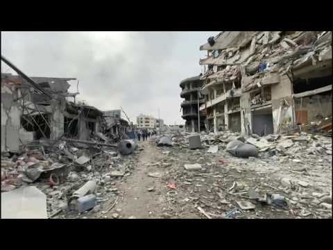 Palestinians walk along destroyed streets in Gaza City
