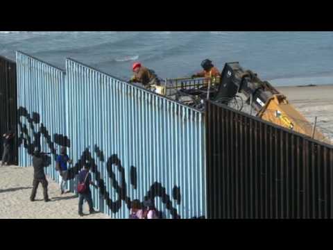 US reinforces border wall in Tijuana as migrants look on