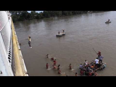 Migrants jump from the Guatemala-Mexico border bridge into river
