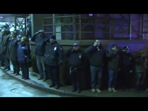 NYPD officers salute their fallen comrades