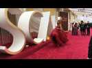 Journalists and TV presenters wait for stars on the Oscars red carpet