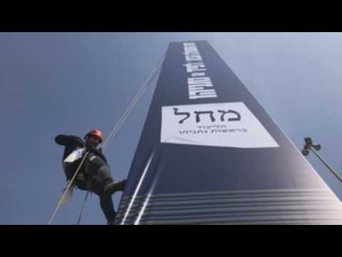 Workers install election posters in Tel Aviv for the next legislative elections