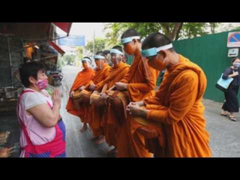 Buddhist monks in Bangkok collect morning alms with face shields against coronavirus