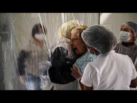 Nursing home residents hug loved ones through a plastic 'hug curtain' amid pandemic