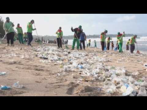 Indonesian workers clean up beach covered with trash in Bali