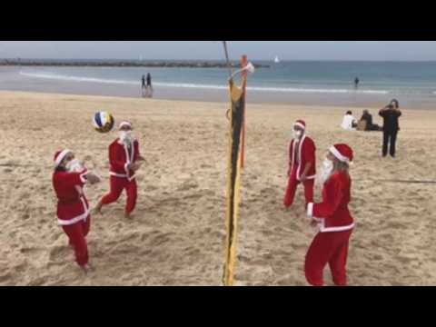 'Santa Clauses' play voleyball on Tel Aviv beach