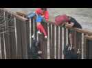 Families with young children attempt to climb Mexico-US border fence