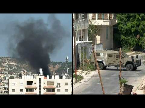 Smoke rises from building as Israeli army vehicles patrol Jenin