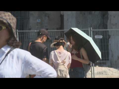 Tourists at the colosseum in Rome fend off high temperatures
