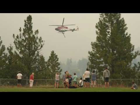 Firefighting helicopters fly through smoky skies over West Kelowna