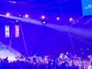 Dans la halle olympique, le public se chauffe sur la chanson "Dans les yeux d'Emilie" de Joe Dassin